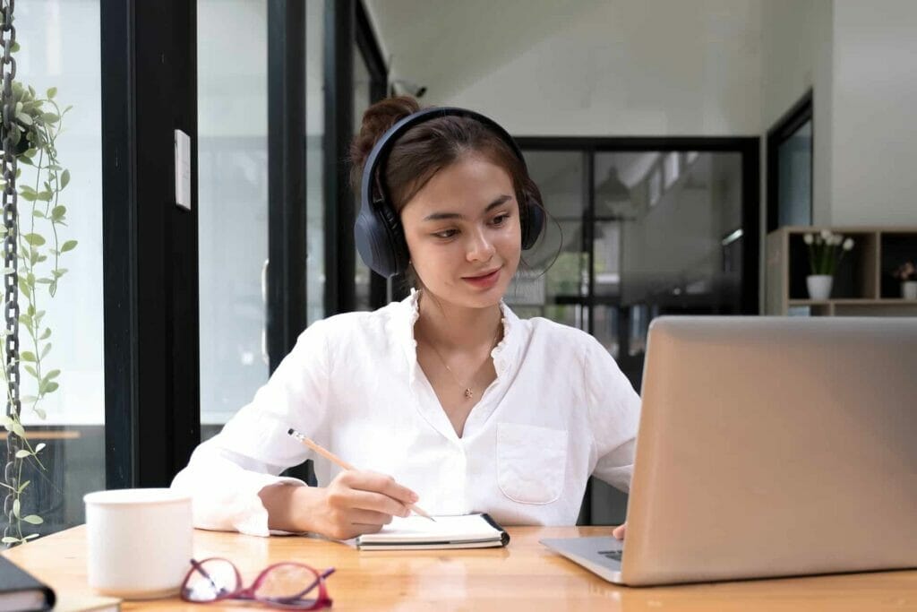 A women wearing headphones listens to the audio instructions from an online quiz as she works at a desk with a laptop.